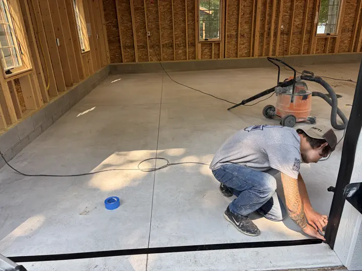 Vacuuming a ground slab and taping its edges before the coating goes down